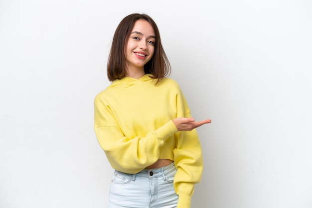 Jeune femme ukrainienne isolée sur fond blanc présentant une idée tout en regardant en souriant vers