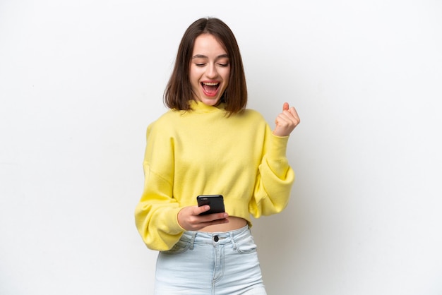 Jeune femme ukrainienne isolée sur fond blanc avec téléphone en position de victoire