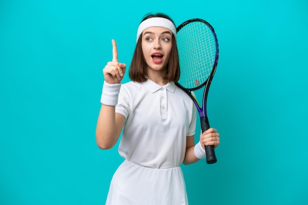 Jeune femme ukrainienne isolée sur fond bleu jouant au tennis et pointant vers le haut