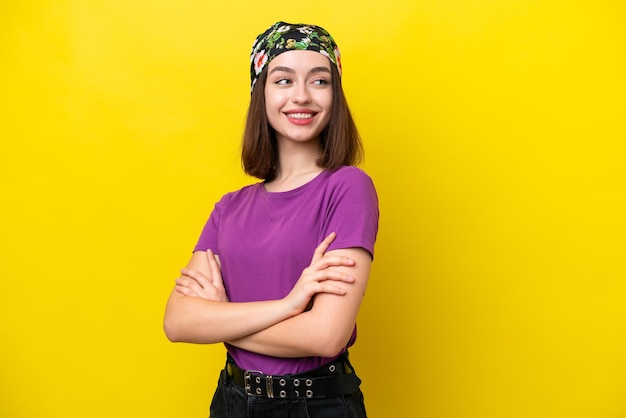 Jeune femme ukrainienne isolée sur fond jaune avec les bras croisés et heureux