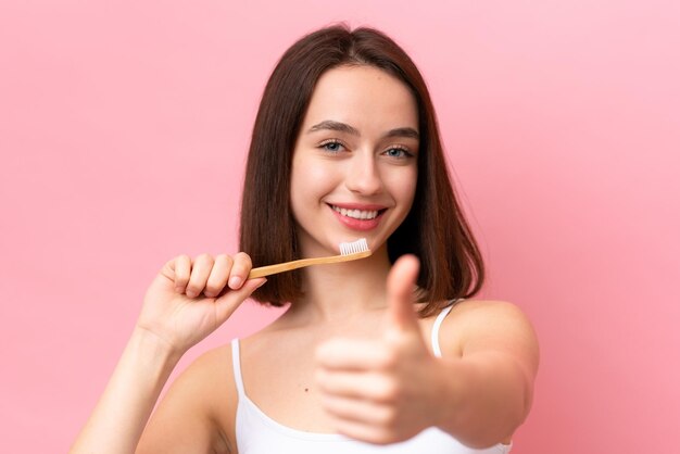 Jeune femme ukrainienne isolée sur fond rose avec une brosse à dents