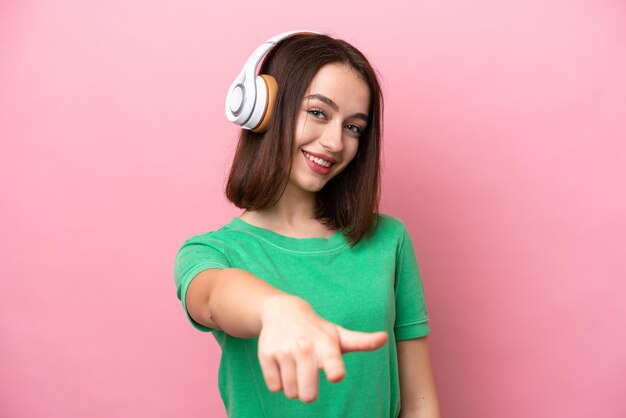 Jeune femme ukrainienne isolée sur fond rose écoutant de la musique