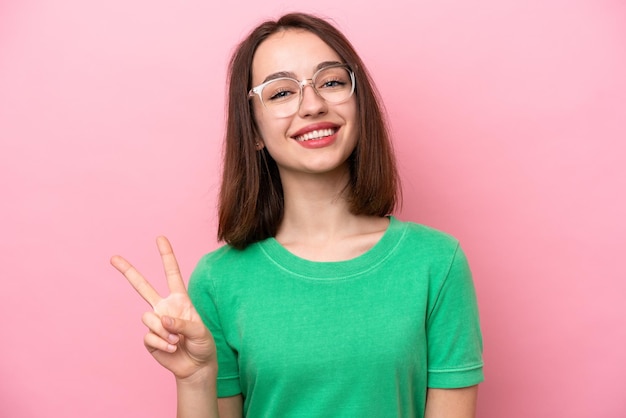 Jeune femme ukrainienne isolée sur fond rose avec des lunettes et faisant signe OK