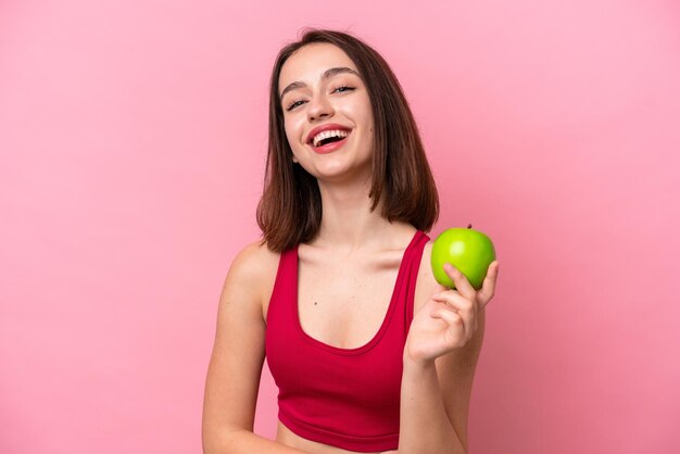 Jeune femme ukrainienne isolée sur fond rose avec une pomme et heureuse