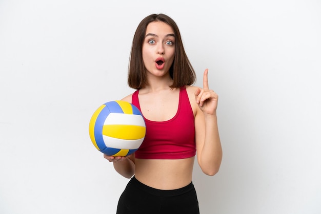 Jeune femme ukrainienne jouant au volley-ball isolé sur fond blanc dans l'intention de réaliser la solution tout en levant un doigt