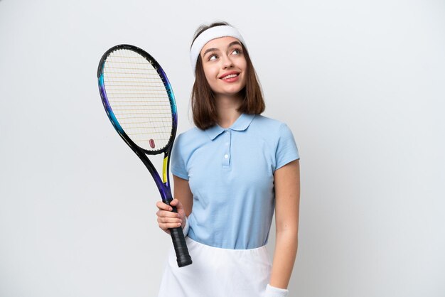 Jeune femme ukrainienne de joueur de tennis d'isolement sur le fond blanc pensant une idée tout en regardant vers le haut