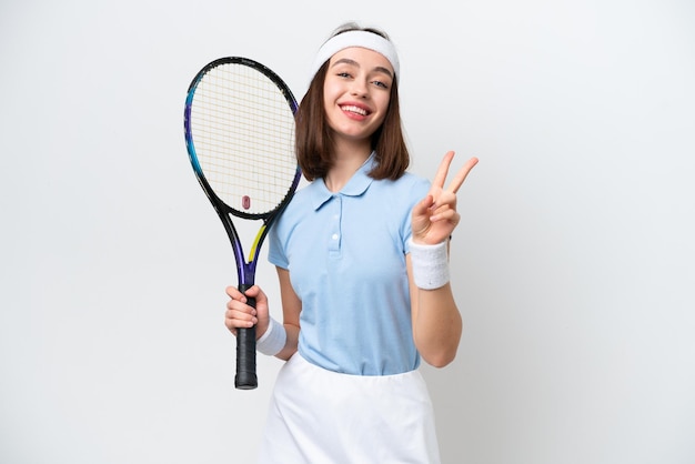 Jeune femme ukrainienne de joueur de tennis d'isolement sur le fond blanc souriant et montrant le signe de victoire