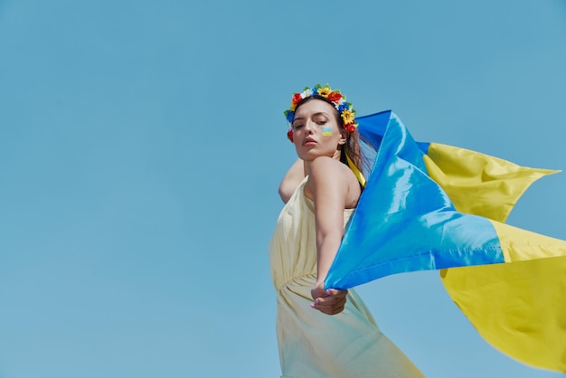 Une jeune femme ukrainienne portant le drapeau national avec le ciel en arrière-plan