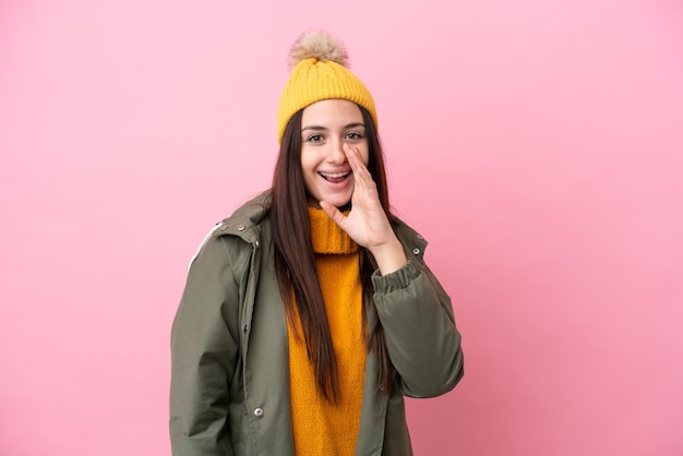 Jeune femme ukrainienne portant une veste d'hiver isolée sur fond rose criant avec la bouche grande ouverte