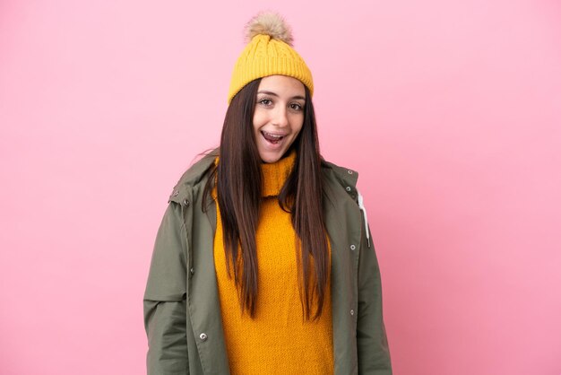 Jeune femme ukrainienne portant une veste d'hiver isolée sur fond rose avec une expression faciale surprise