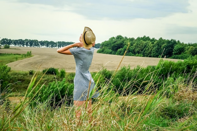 une jeune femme ukrainienne se dresse sur fond de champs de blé fauchés