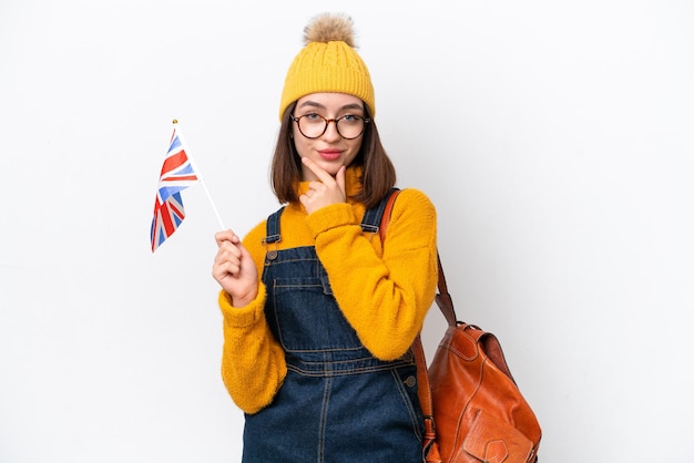 Jeune femme ukrainienne tenant un drapeau du Royaume-Uni isolé sur fond blanc pensant