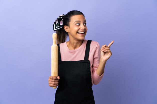 Jeune femme en uniforme de chef ayant l'intention de réaliser la solution tout en levant un doigt