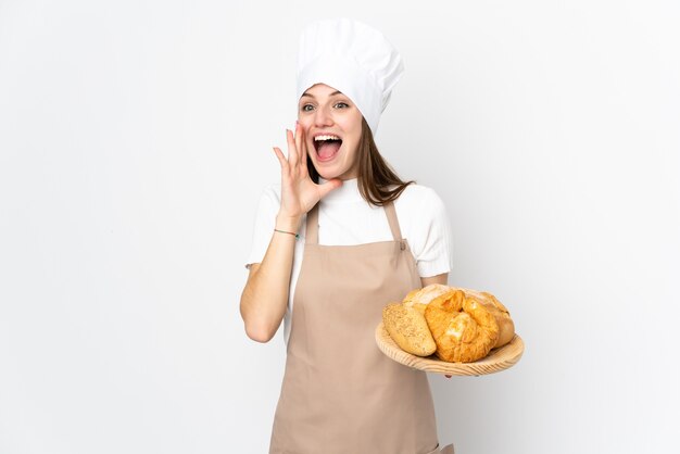 Jeune femme en uniforme de chef sur mur blanc criant avec la bouche grande ouverte