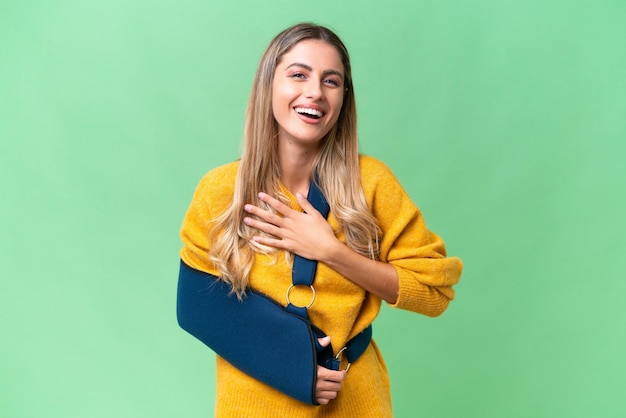 Jeune femme uruguayenne avec bras cassé et portant une écharpe sur fond isolé souriant beaucoup