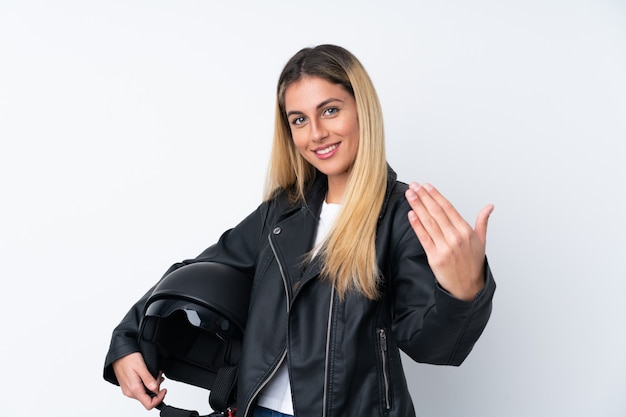 Jeune femme uruguayenne avec un casque de moto sur un mur blanc isolé invitant à venir