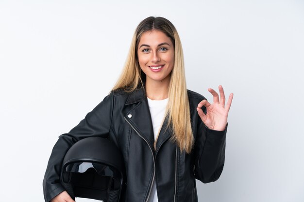 Jeune femme uruguayenne avec un casque de moto sur mur isolé mur blanc montrant un signe ok avec les doigts