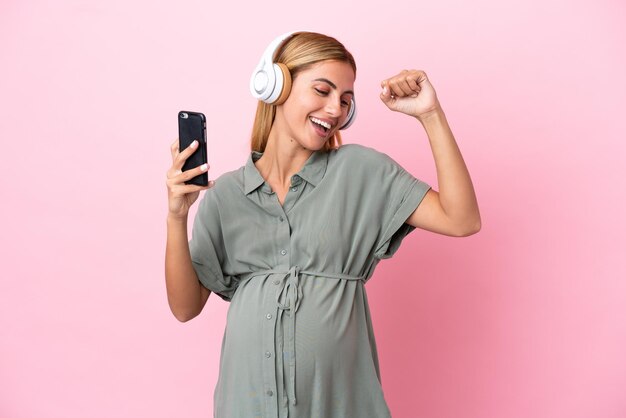 Jeune femme uruguayenne isolée sur fond bleu enceinte et dansant tout en écoutant de la musique