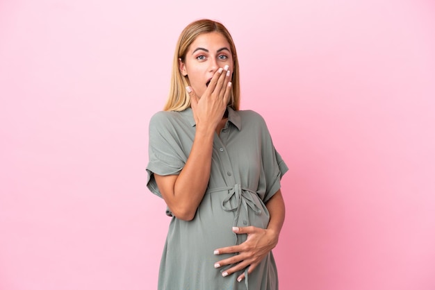 Jeune femme uruguayenne isolée sur fond bleu enceinte et faisant un geste surprise