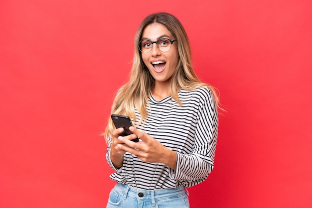 Jeune femme uruguayenne isolée sur fond rouge surprise et envoyant un message