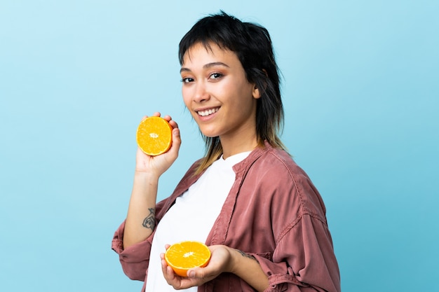 Jeune femme uruguayenne sur mur bleu tenant une orange