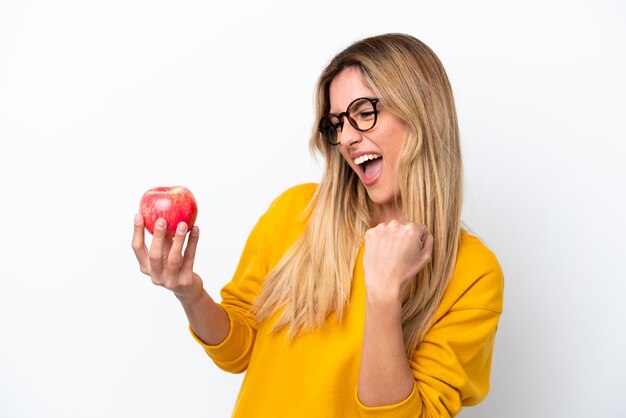 Jeune femme uruguayenne avec une pomme isolée sur fond blanc célébrant une victoire