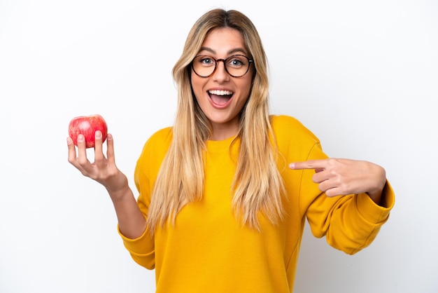 Jeune femme uruguayenne avec une pomme isolée sur fond blanc avec une expression faciale surprise