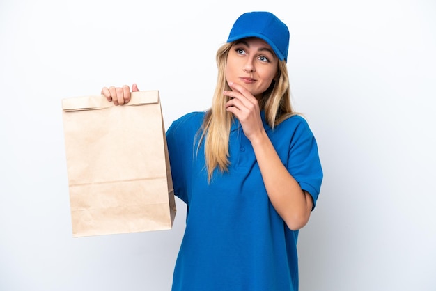 Jeune femme uruguayenne prenant un sac de plats à emporter isolé sur fond blanc et levant les yeux