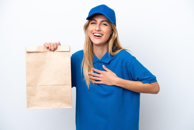 Jeune femme uruguayenne prenant un sac de plats à emporter isolé sur fond blanc souriant beaucoup