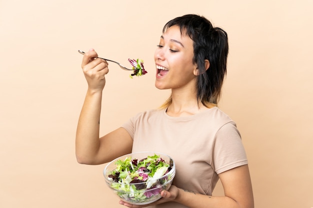 Jeune femme uruguayenne avec salade sur mur isolé