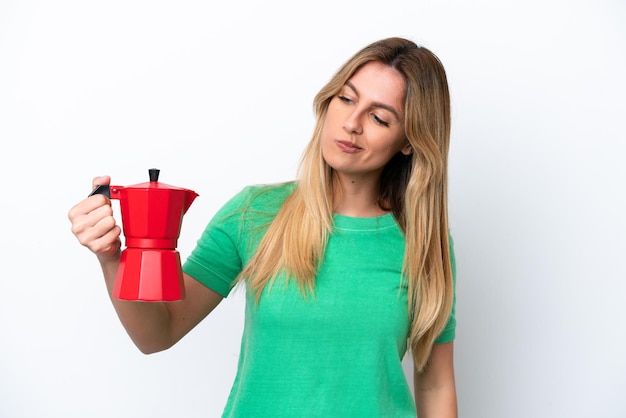 Jeune femme uruguayenne tenant une cafetière isolée sur fond blanc avec une expression triste