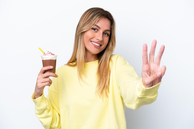 Jeune femme uruguayenne tenant Frappuccino isolé sur fond blanc heureux et comptant trois avec les doigts