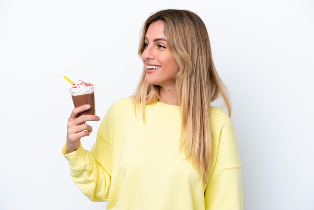Jeune femme uruguayenne tenant Frappuccino isolé sur fond blanc regardant sur le côté et souriant