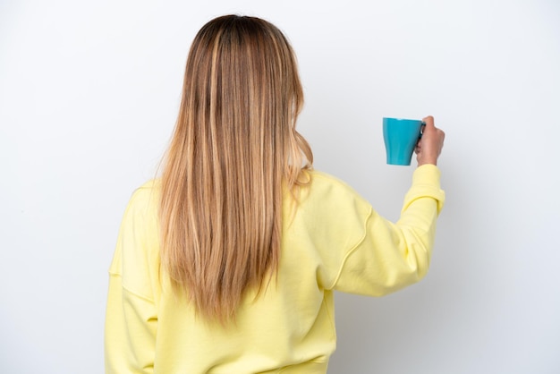 Jeune femme uruguayenne tenant une tasse de café isolé sur fond blanc en position arrière