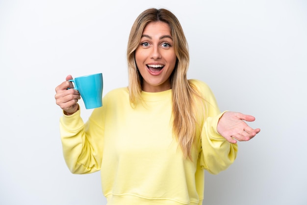 Jeune femme uruguayenne tenant une tasse de café isolée sur fond blanc avec une expression faciale choquée