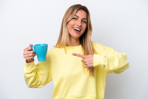 Jeune femme uruguayenne tenant une tasse de café isolée sur fond blanc et la pointant