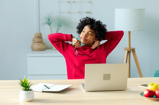 Une jeune femme utilisant un ordinateur portable alors qu'elle est assise sur la table