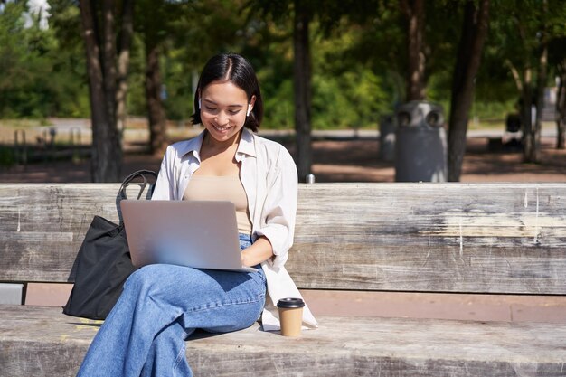 Photo une jeune femme utilisant un ordinateur portable assise sur un banc