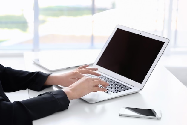 Jeune femme utilisant un ordinateur portable pour rechercher des informations sur Internet à table