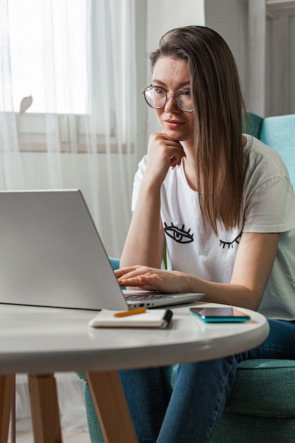 Jeune femme utilisant un ordinateur portable pour travailler à la maison