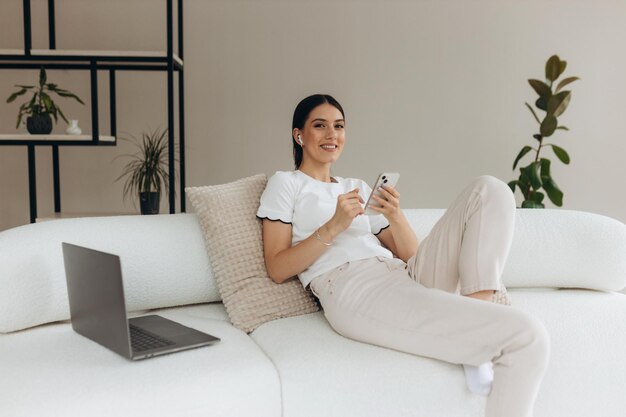 Jeune femme utilisant ses gadgets et se relaxant à la maison