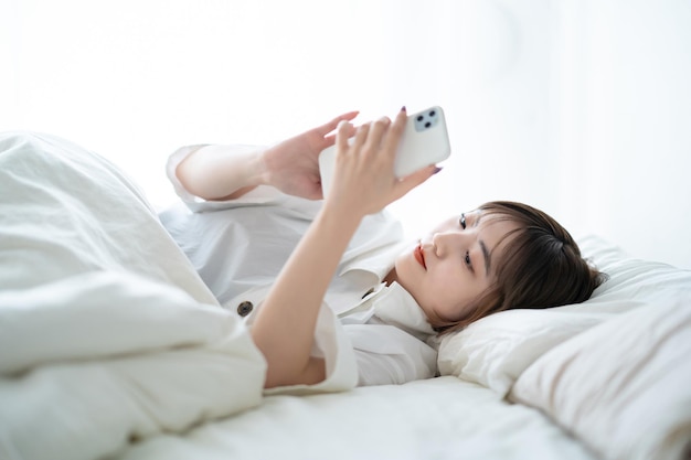 Jeune femme utilisant un smartphone sur le lit