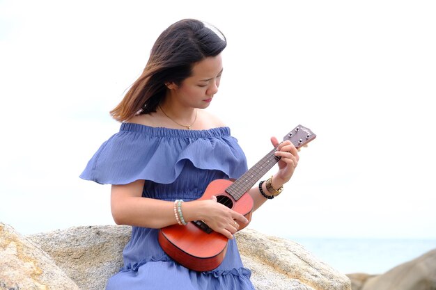 Photo une jeune femme utilisant un smartphone par la mer contre le ciel