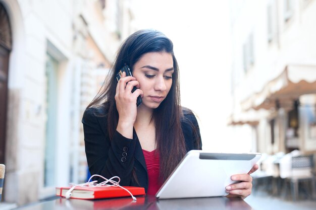 Jeune femme utilisant une tablette numérique et un téléphone portable