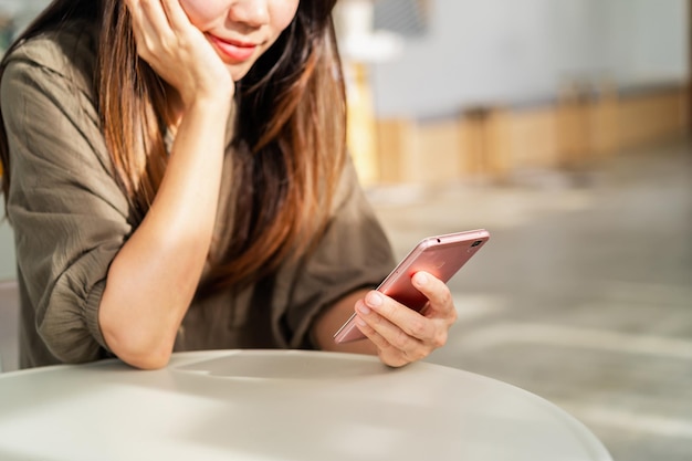 Jeune femme utilisant un téléphone intelligent et se relaxant au café, mode de vie moderne
