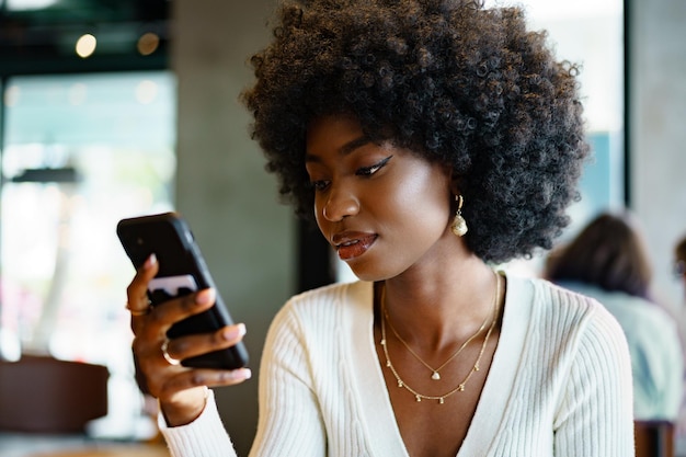 Jeune femme utilisant un téléphone portable au café