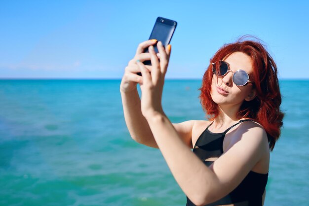 Jeune femme utilisant un téléphone portable contre la mer