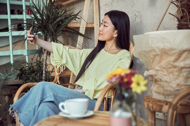 Jeune femme utilisant un téléphone portable dans un café