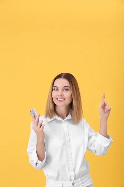 Jeune femme utilisant un téléphone portable sur fond jaune