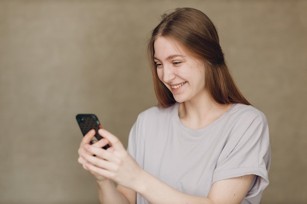 Jeune femme utilisant un téléphone portable sur fond marron